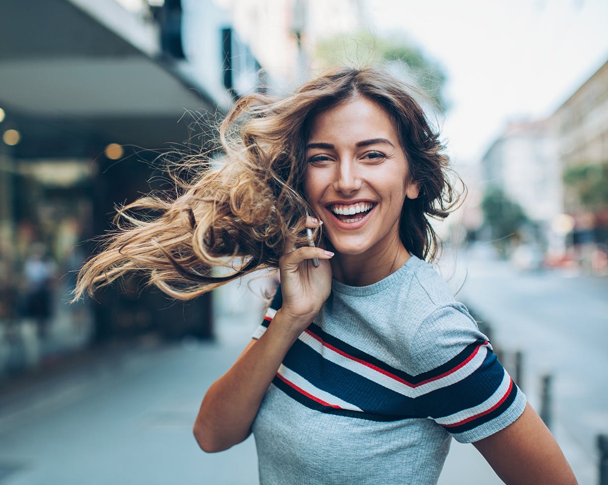 Woman in a striped t-shirt outside laughing