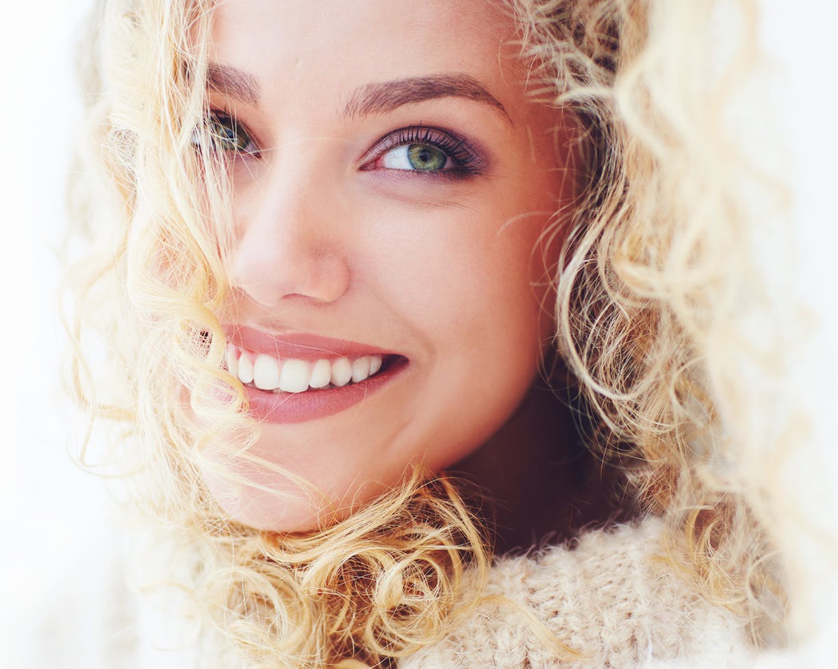 Close-up of a blonde woman  in a sweater smiling