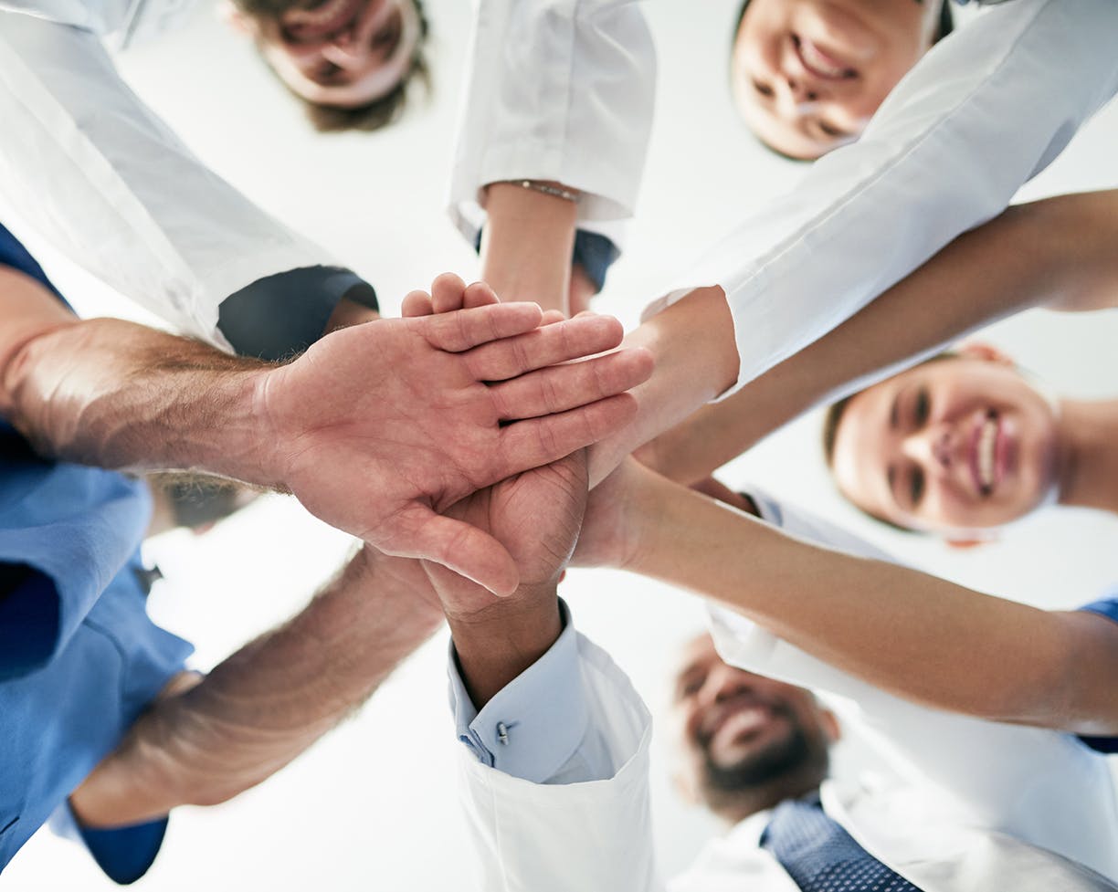 A circle of doctors putting their hand in the middle