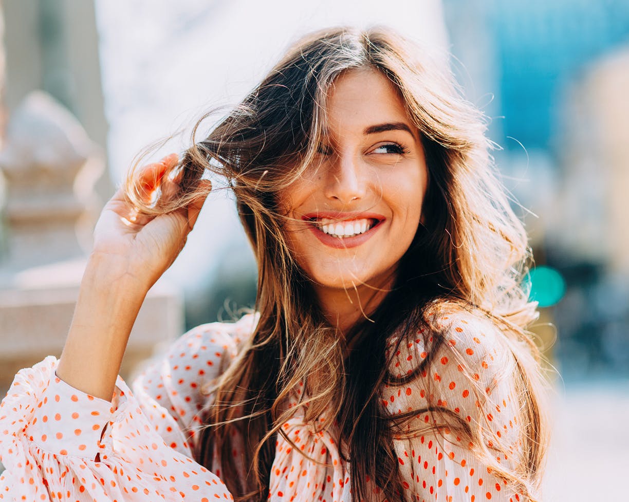 Woman in polka-dot shirt twirling her hair