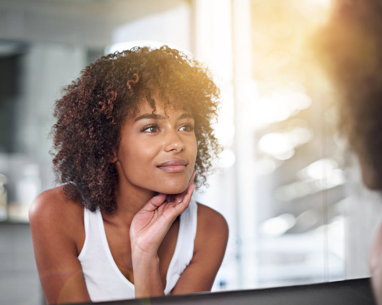 Woman touching her face looking in a mirror