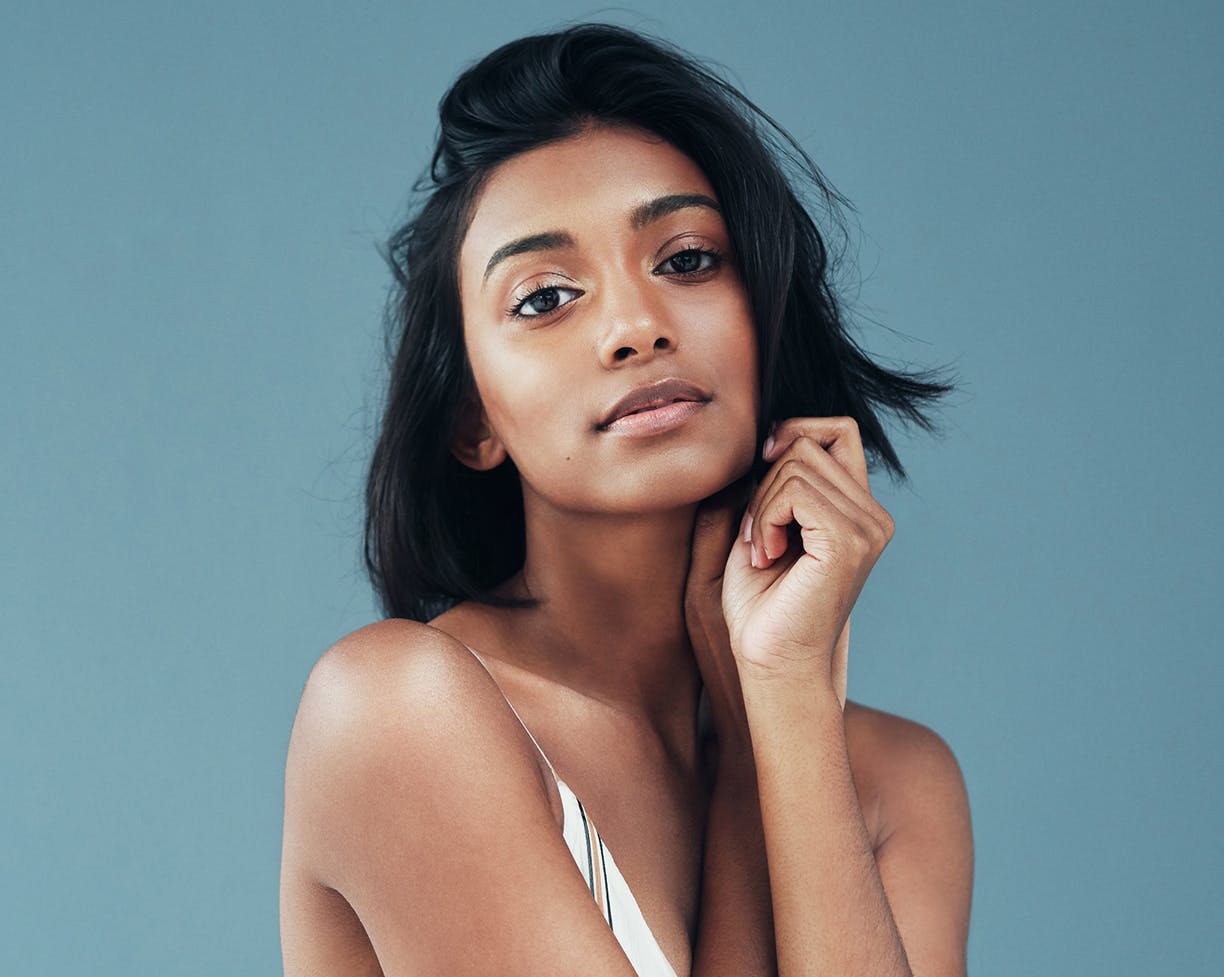 Woman with black hair touching her face