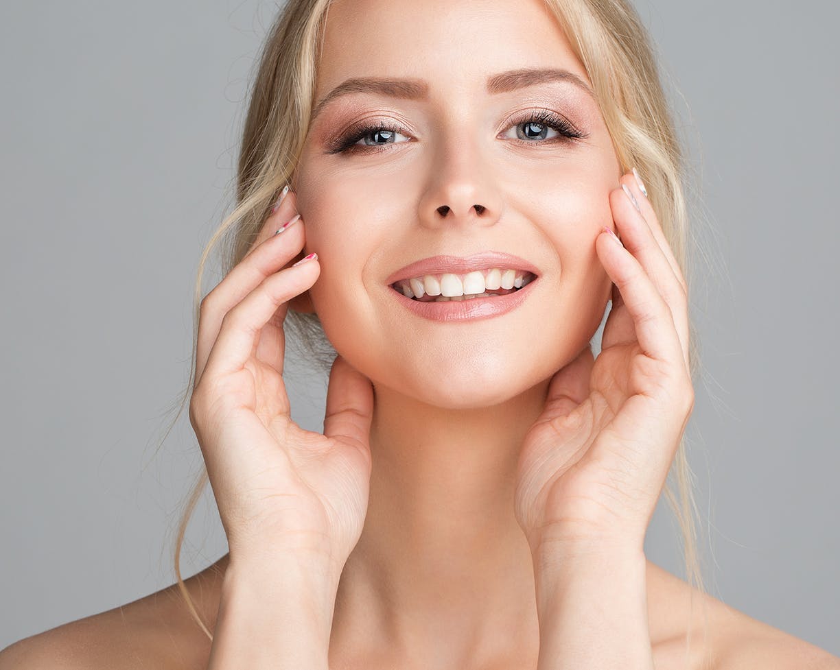 Blonde woman touching her face and smiling