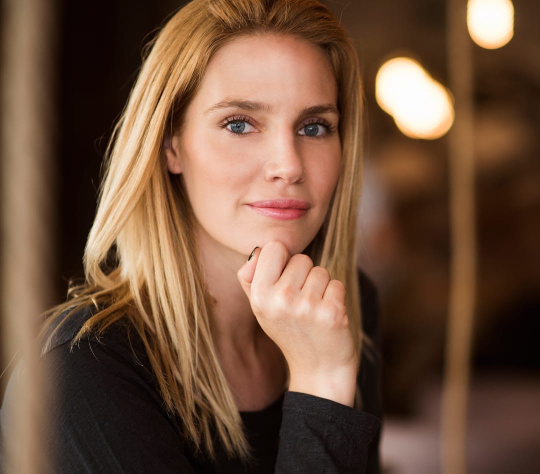 Blonde woman touching her chin looking at camera