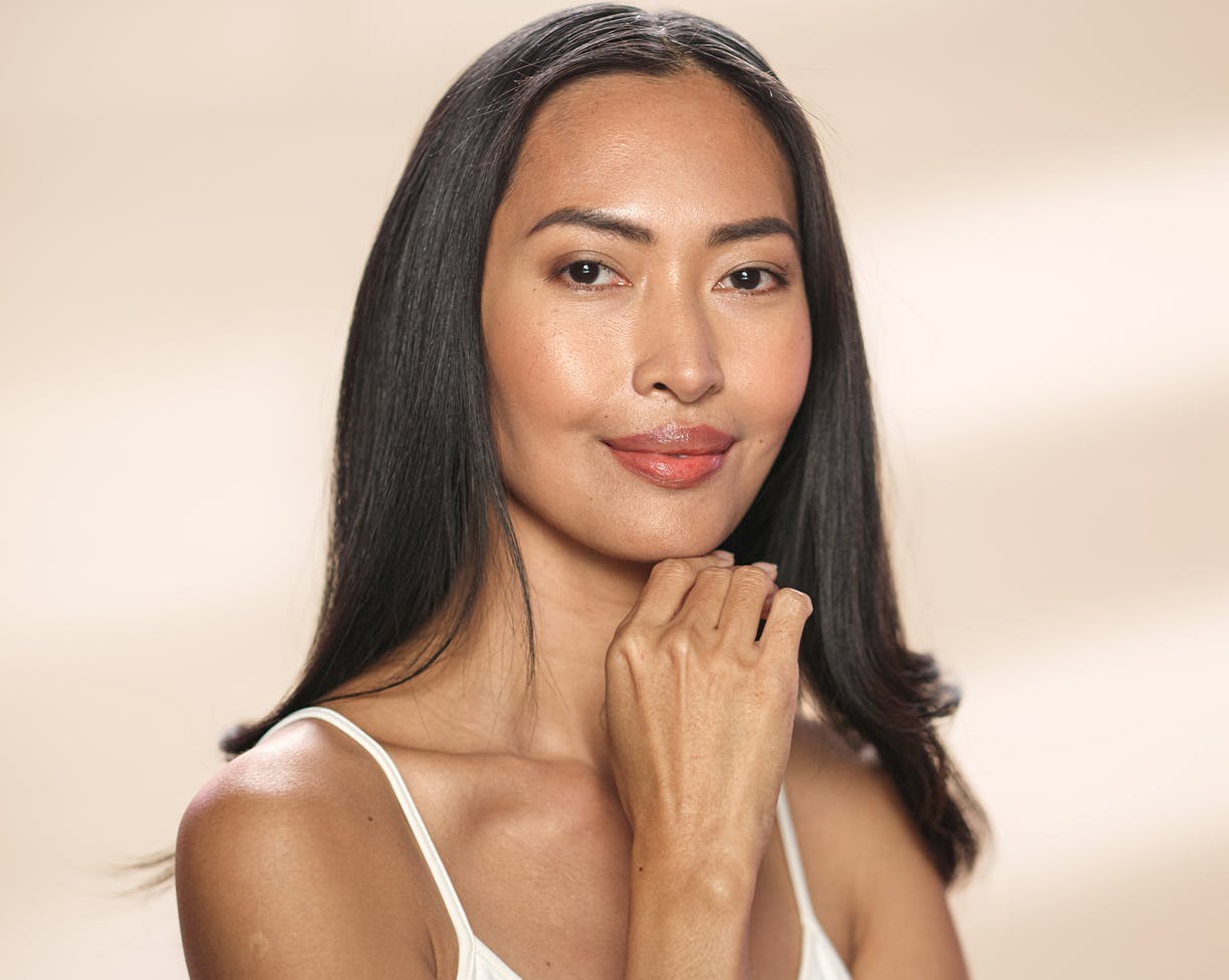 Dark-haired woman in a white blouse touching her face