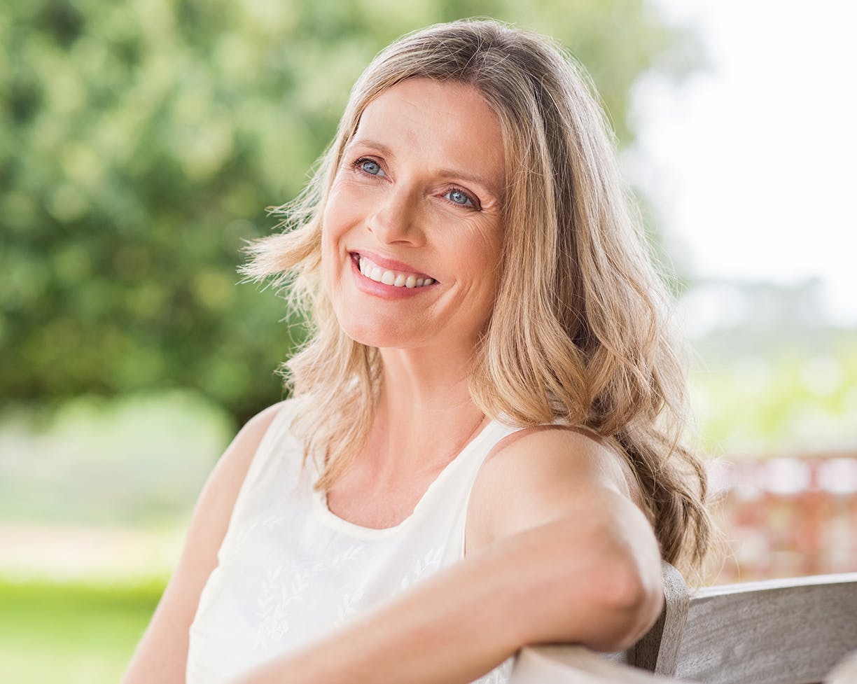 Woman in a white top sitting outside