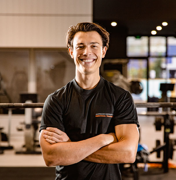 Male trainer with arms crossed inside a gym