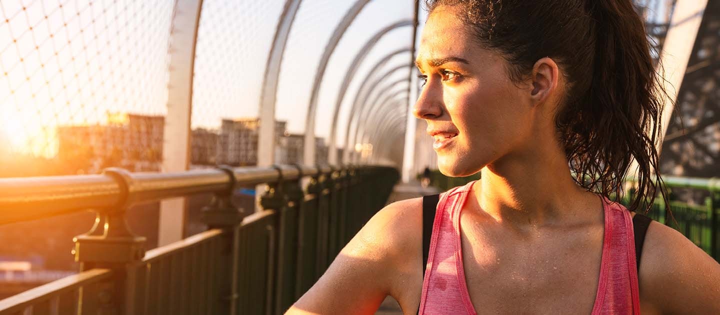 Female looking into sun rise after early morning run 