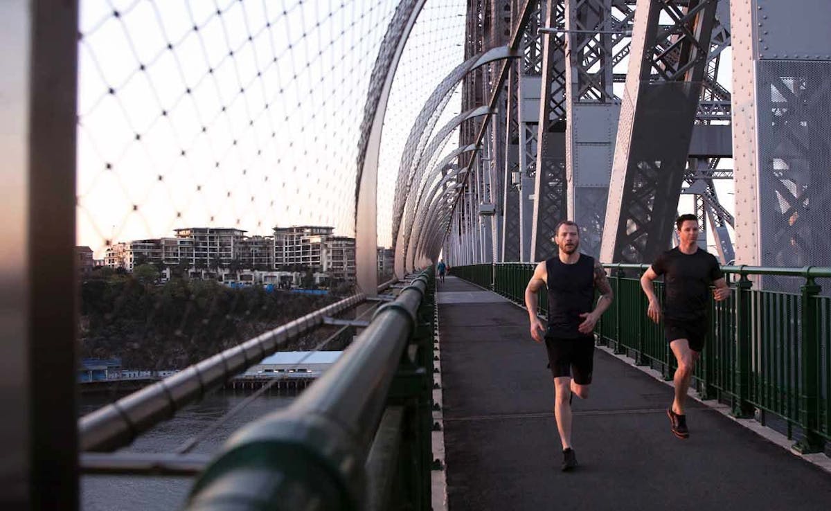 personal trainer and client running on a bridge