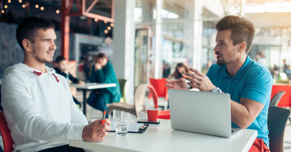 Two guys sitting at a cafe talking