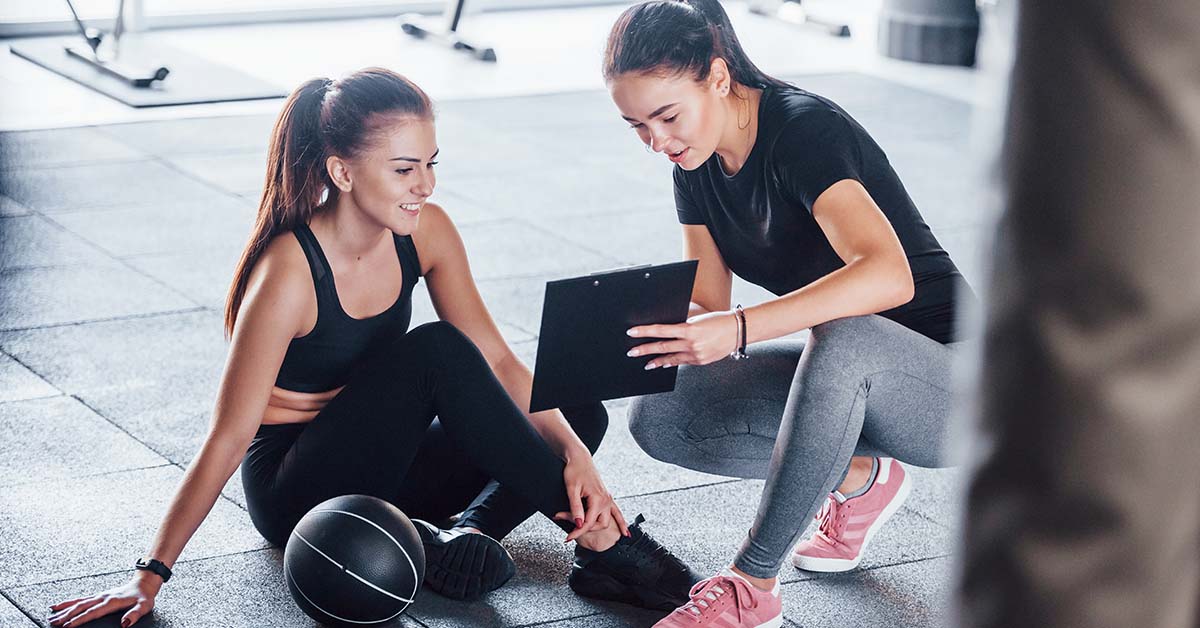 personal trainer with clipboard showing results to client