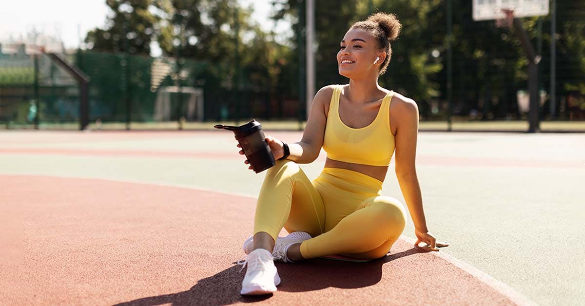 smiling lady in sportswear holding a shaker