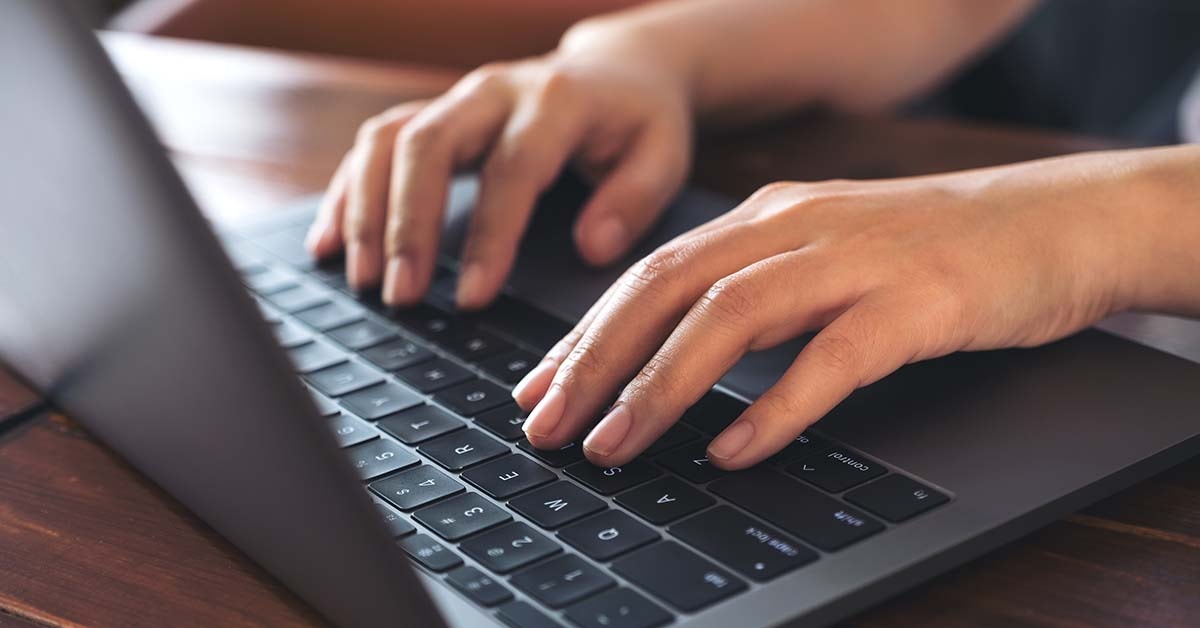 woman's hands working and typing on laptop keyboard