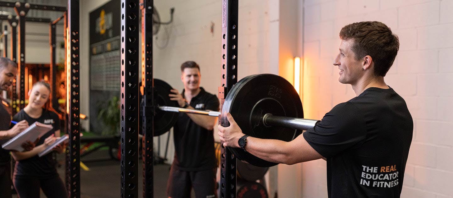 men putting weights on a bar