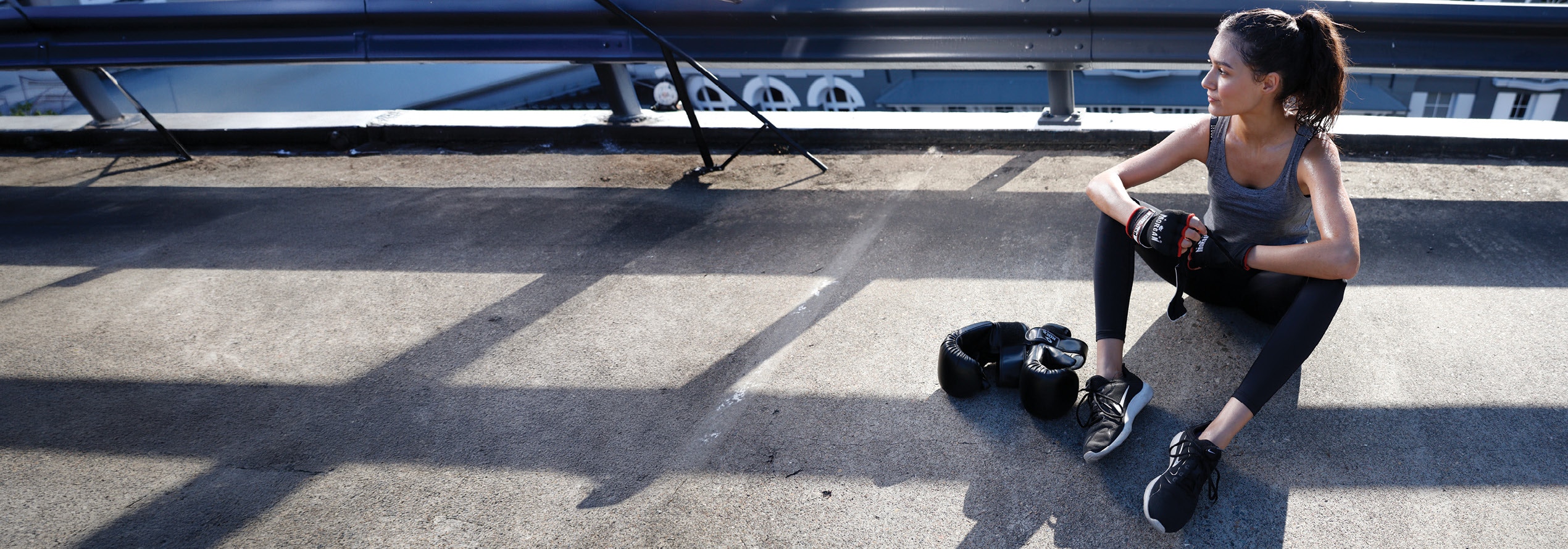 Woman resting beside boxing gloves after a workout in a gym