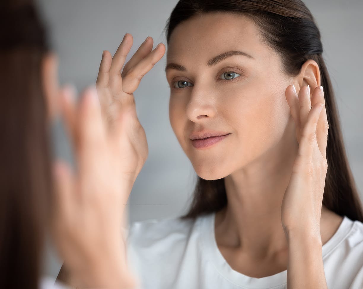 Woman looking at her face in a mirror