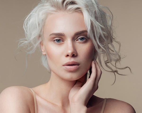 woman with white hair touching face