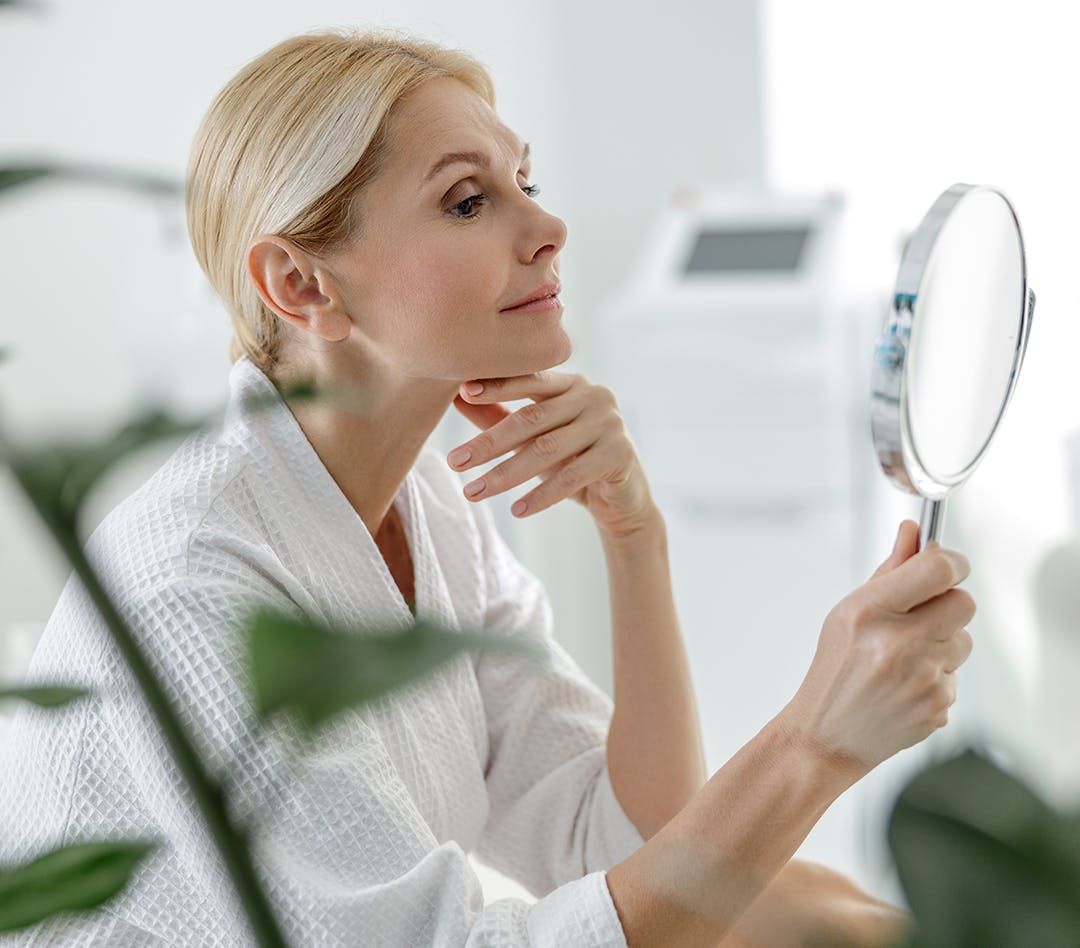 Woman looking at herself in a handheld mirror