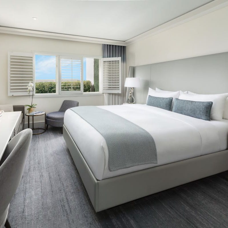 bed in a hotel room with a desk and chair