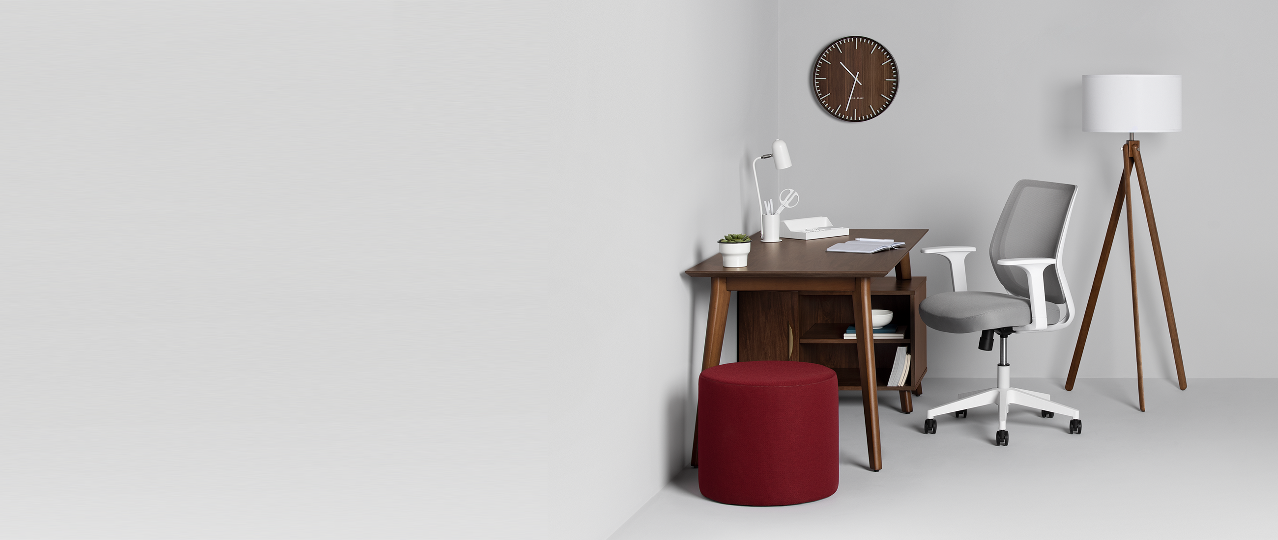 Office set up with desk, chair, pouf, lamp, and clock.