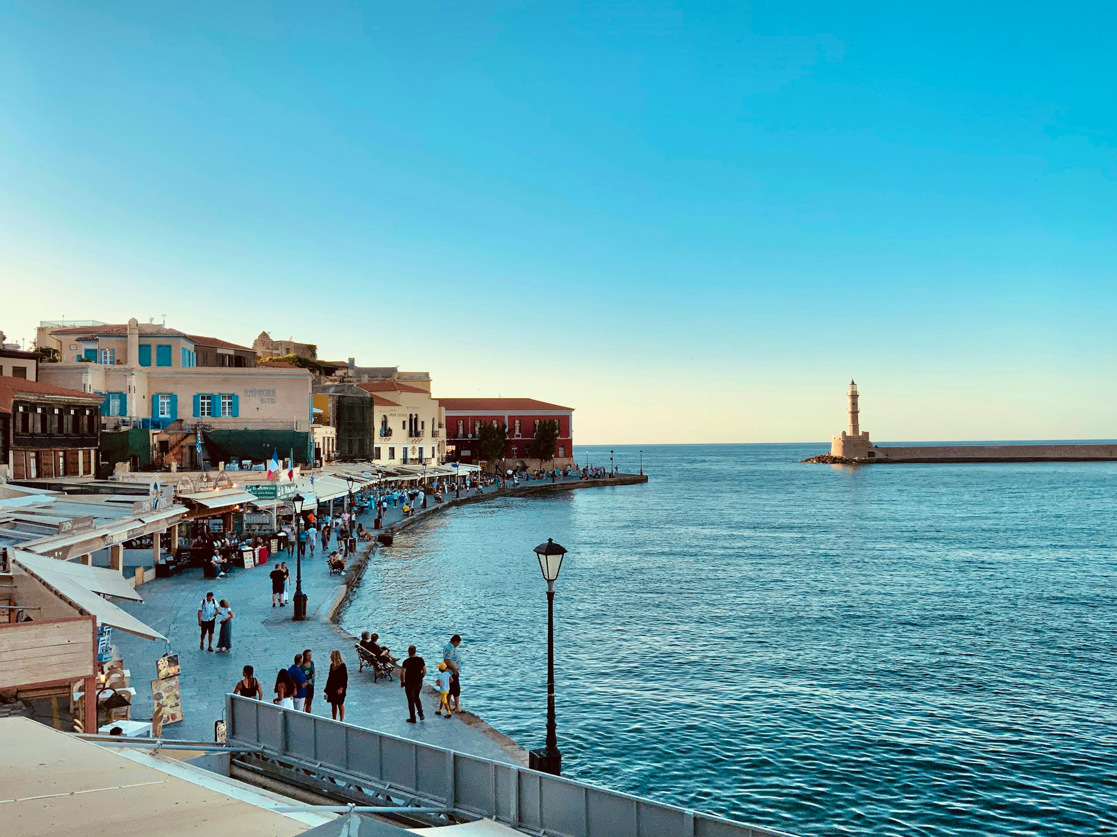 a group of people walking along a pier next to the ocean