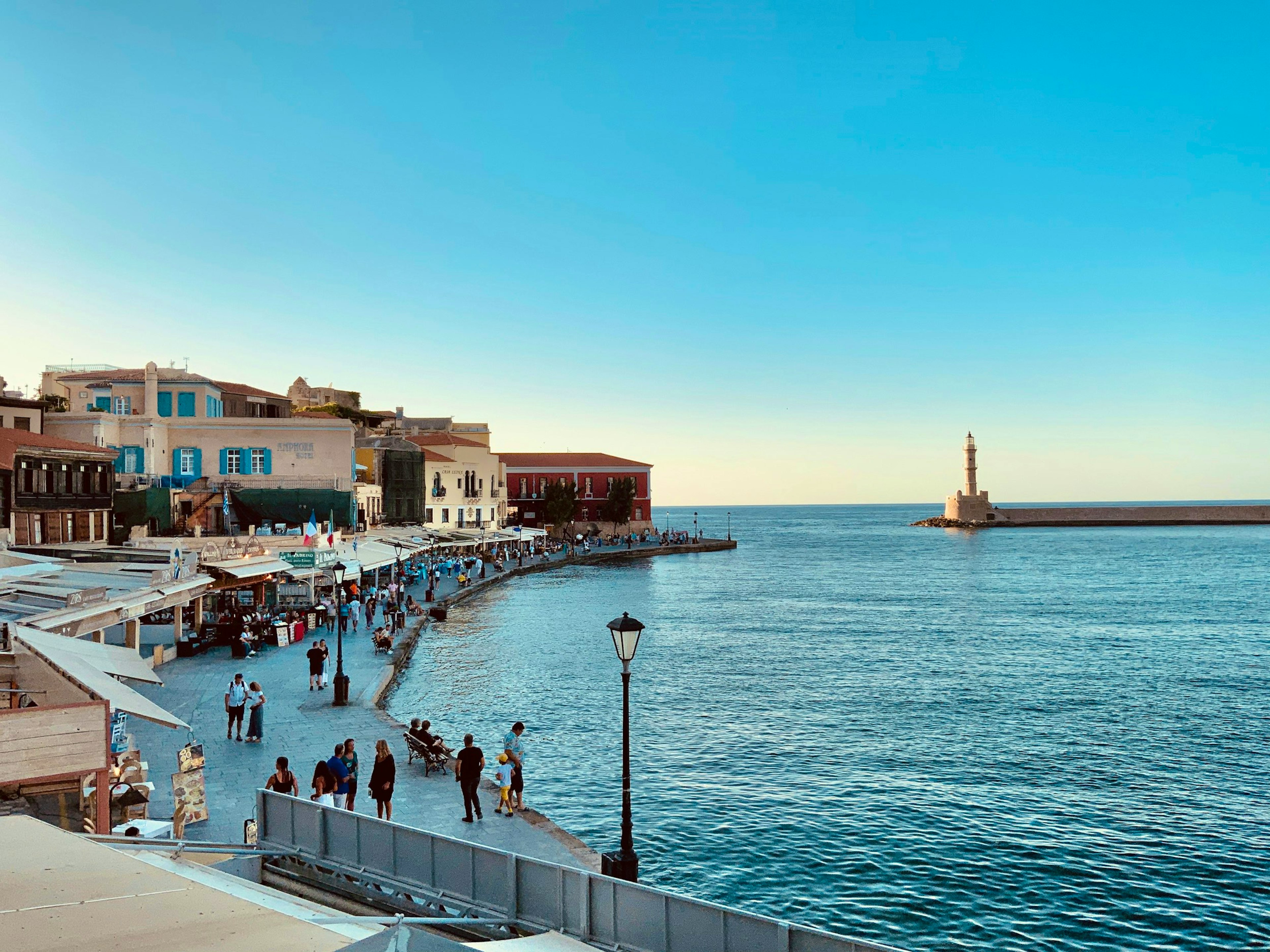 a group of people walking along a pier next to the ocean