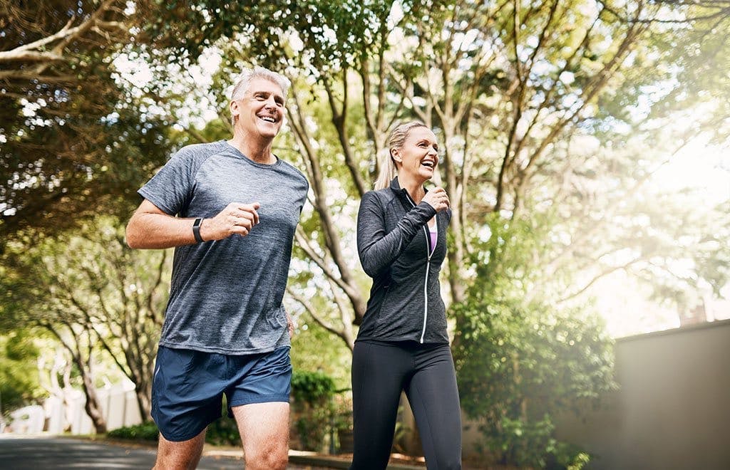 An older man and woman jogging outside