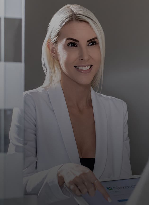 Blonde patient in a white blazer pointing at an iPad