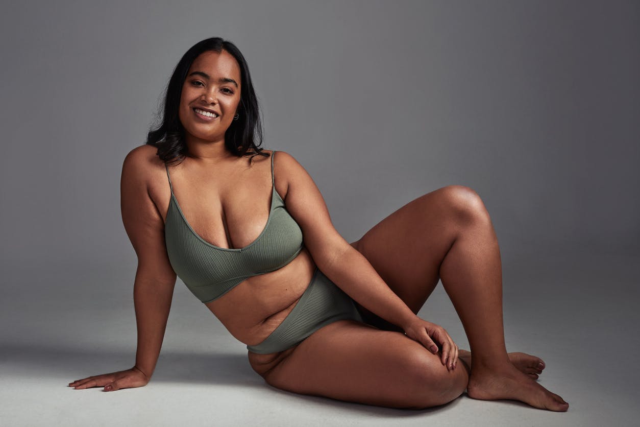 Plus size model wearing green bikini in a studio shoot smiles at teh camera. Her physic emulate the potential results with weightloss surgery in Weston, FL