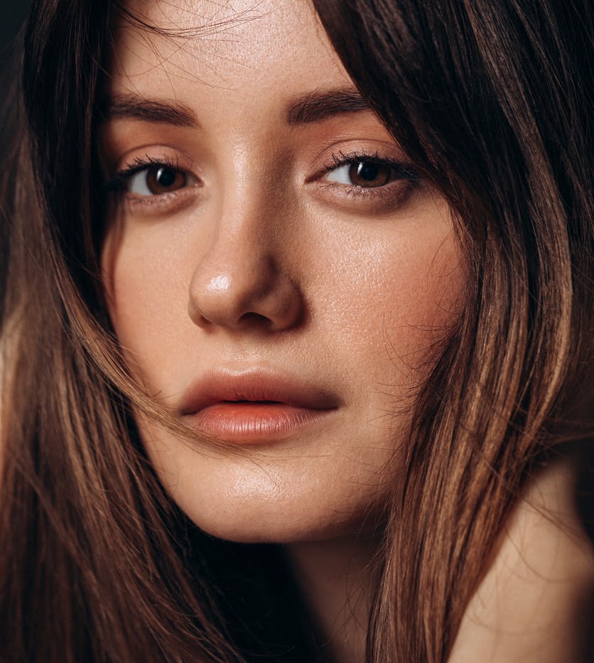 Beautfiul woman with long brown hair looks at the camera in a studio shoot. Her wrinkle free face shows the potential results of BOTOX in Fort Lauderdale with Dr. Shuster