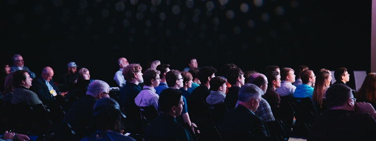 crowd of people sitting on chairs inside room