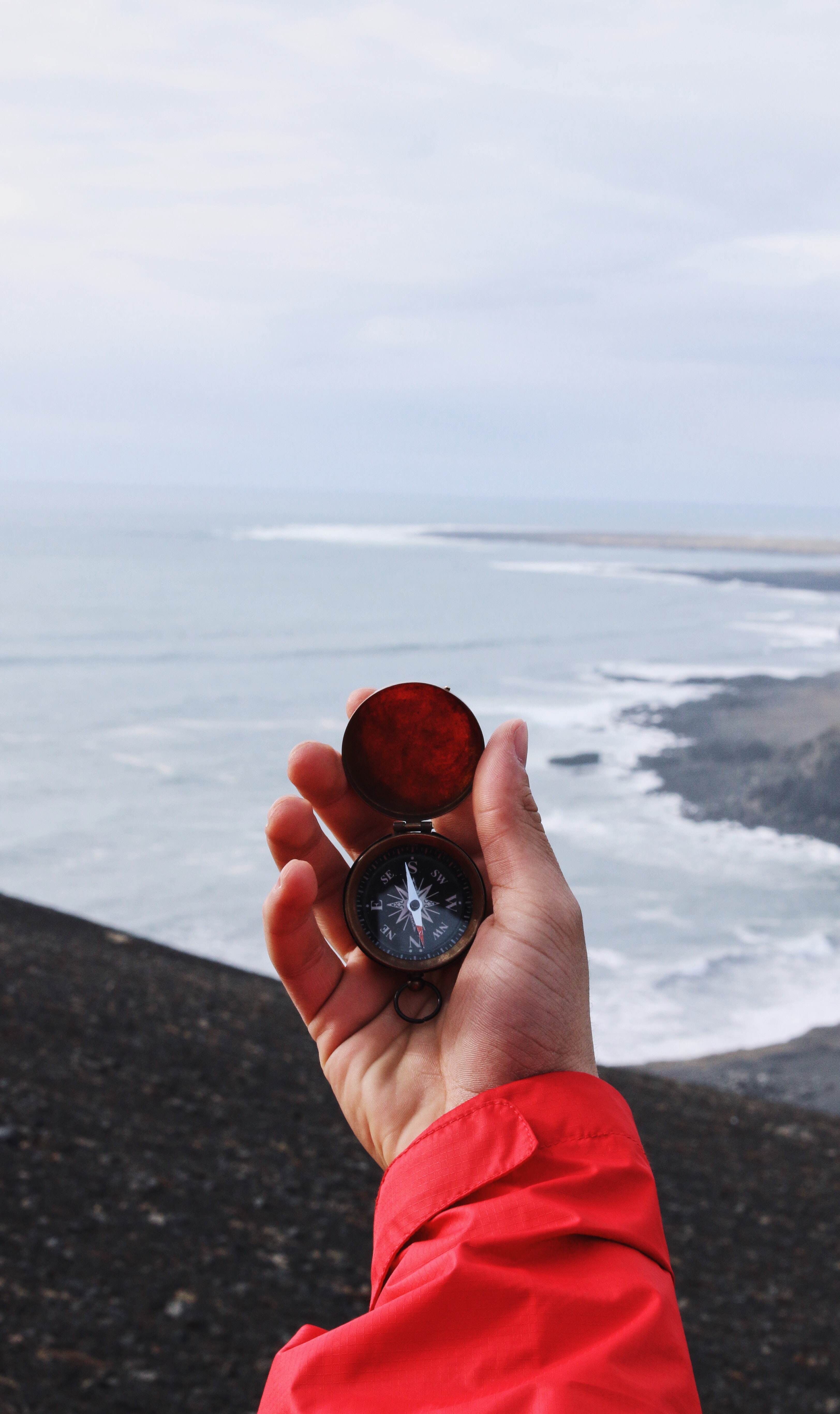 holding a compass in front of the sea