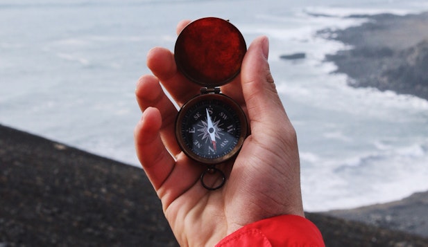 holding a compass in front of the sea