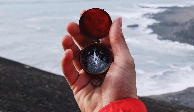holding a compass in front of the sea