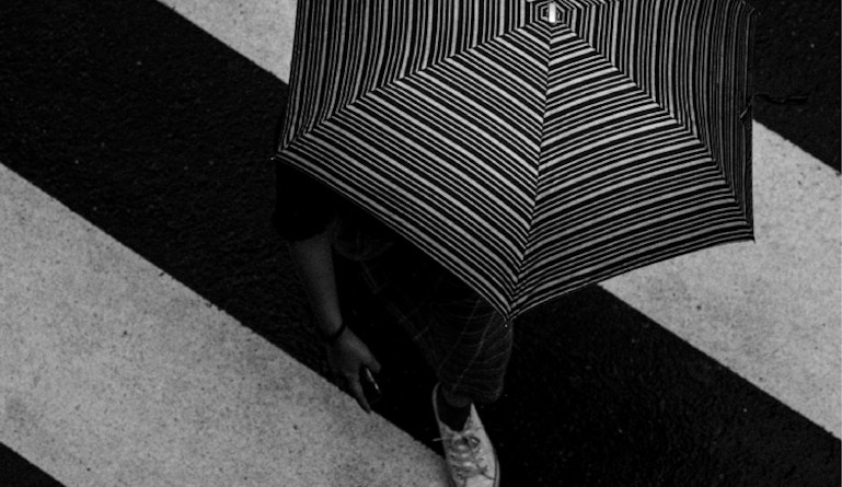 crossing the street with a black & white umbrella