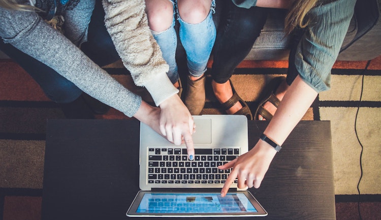 three person pointing the silver laptop computer