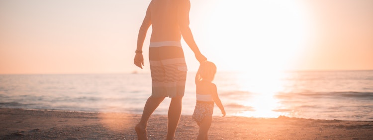 man holding girl heading towards sea