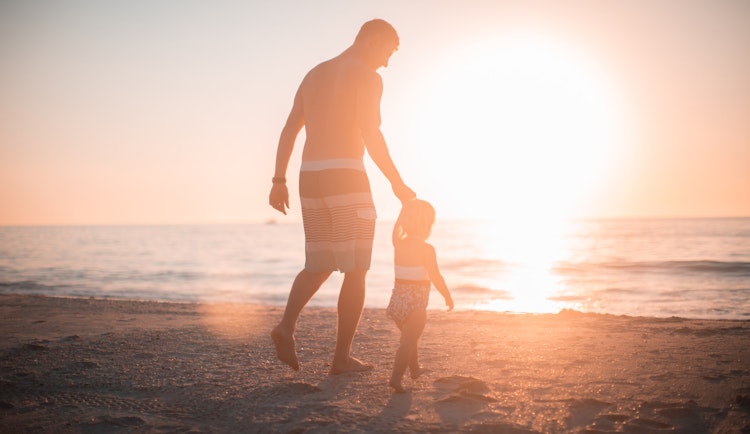 man holding girl heading towards sea