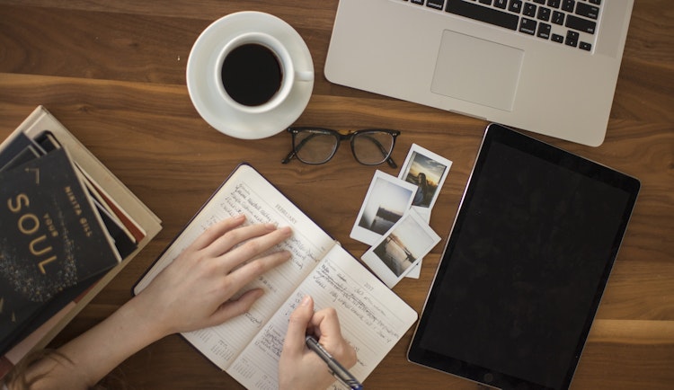 person holding ballpoint pen writing on notebook