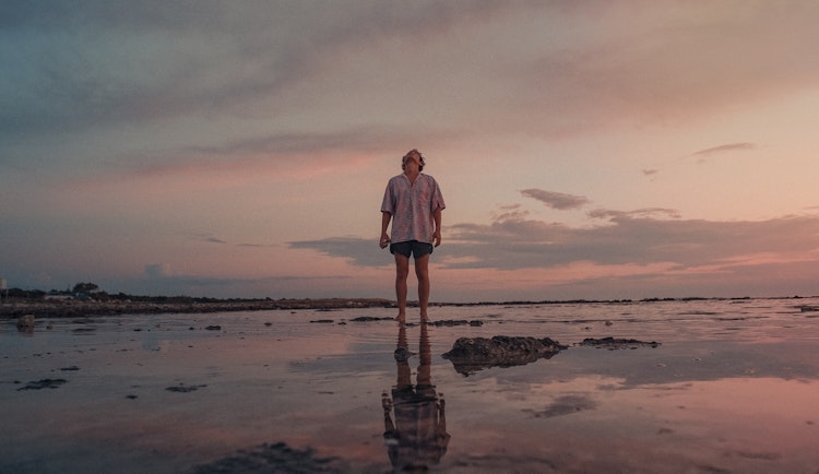 woman in white dress standing on beach during sunset