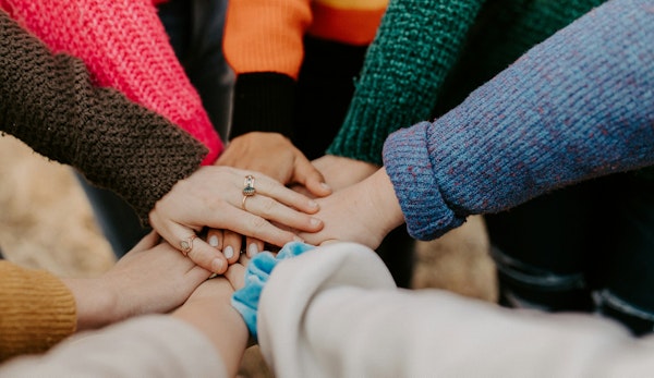 person in red sweater holding babys hand