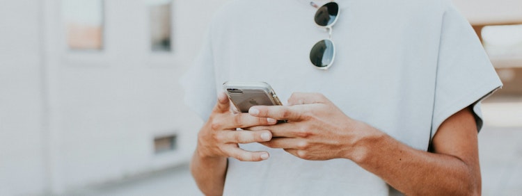 man in white crew-neck top using smartphone outdoors
