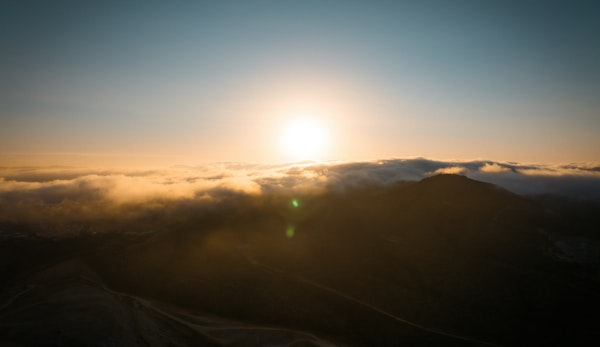 the sun is setting over the clouds in the mountains