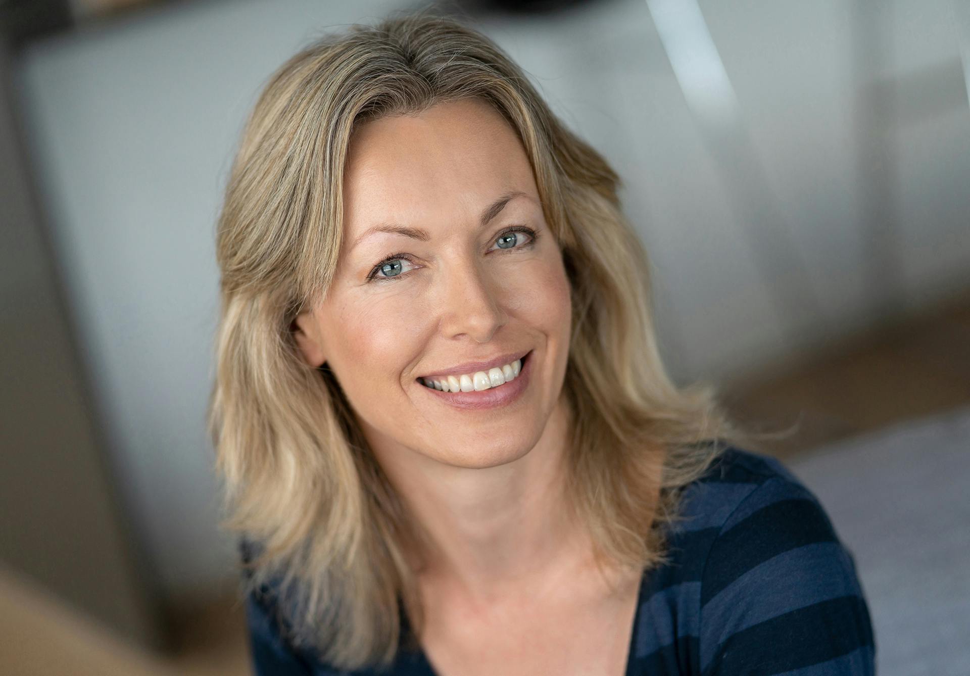 woman with blonde hair wearing a blue and black striped shirt