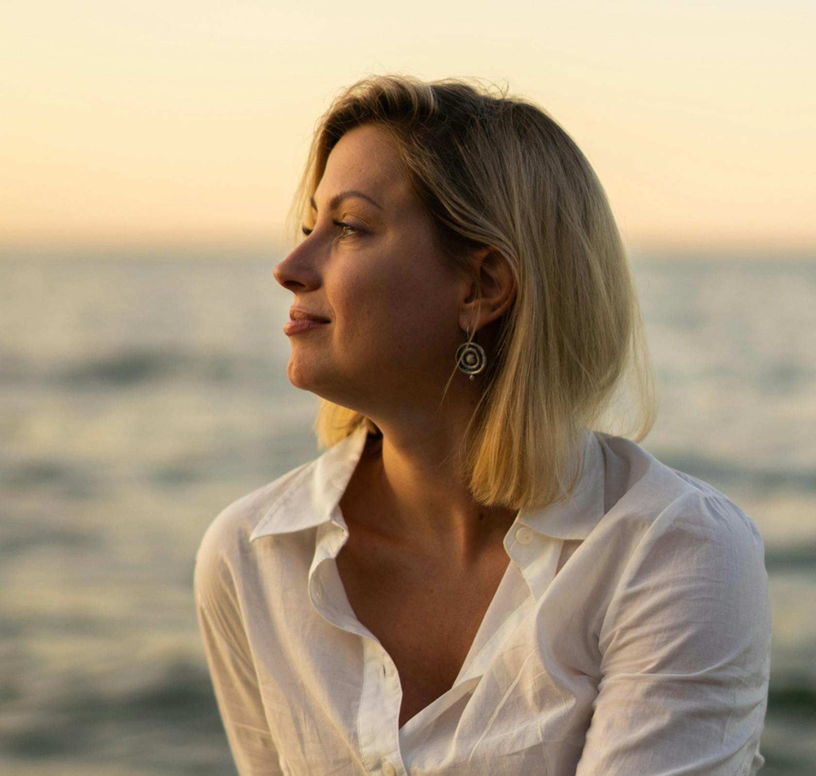 blond woman in white shirt looking out over the ocean