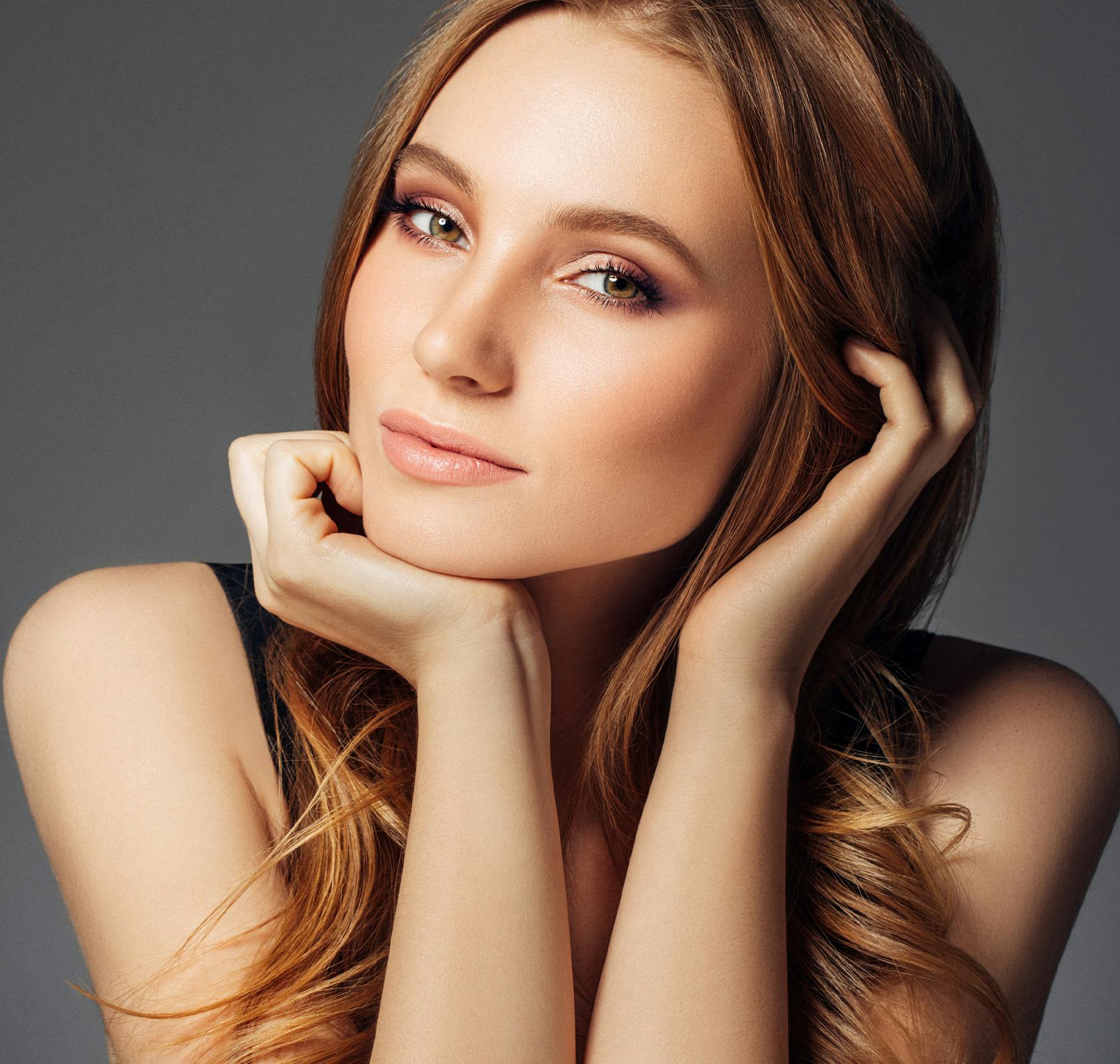 Woman with strawberry blonde hair, resting her chin on her hand