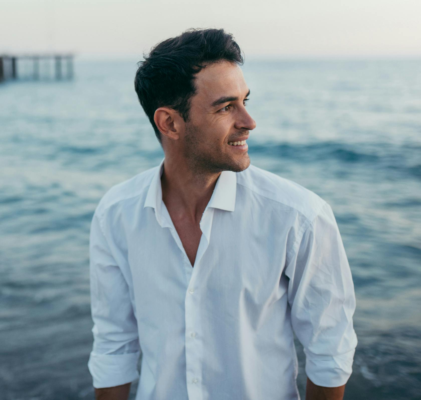 there is a man standing in front of the ocean looking away