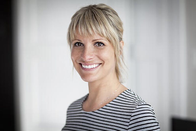 Woman with blonde hair pulled pack, smiling and wearing a striped shirt