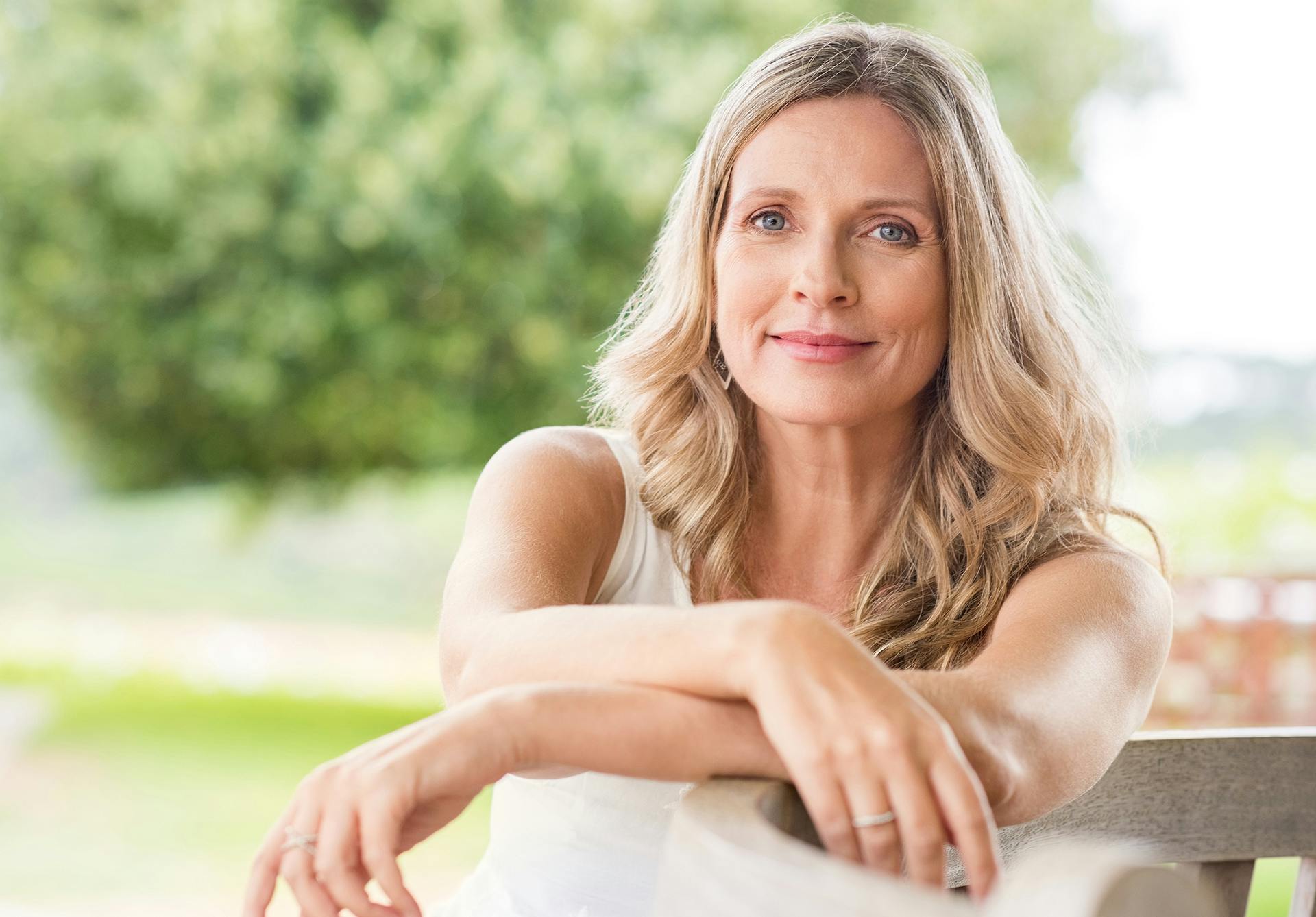 Middle aged blonde woman sitting down with her arms crossed in front of her lazily