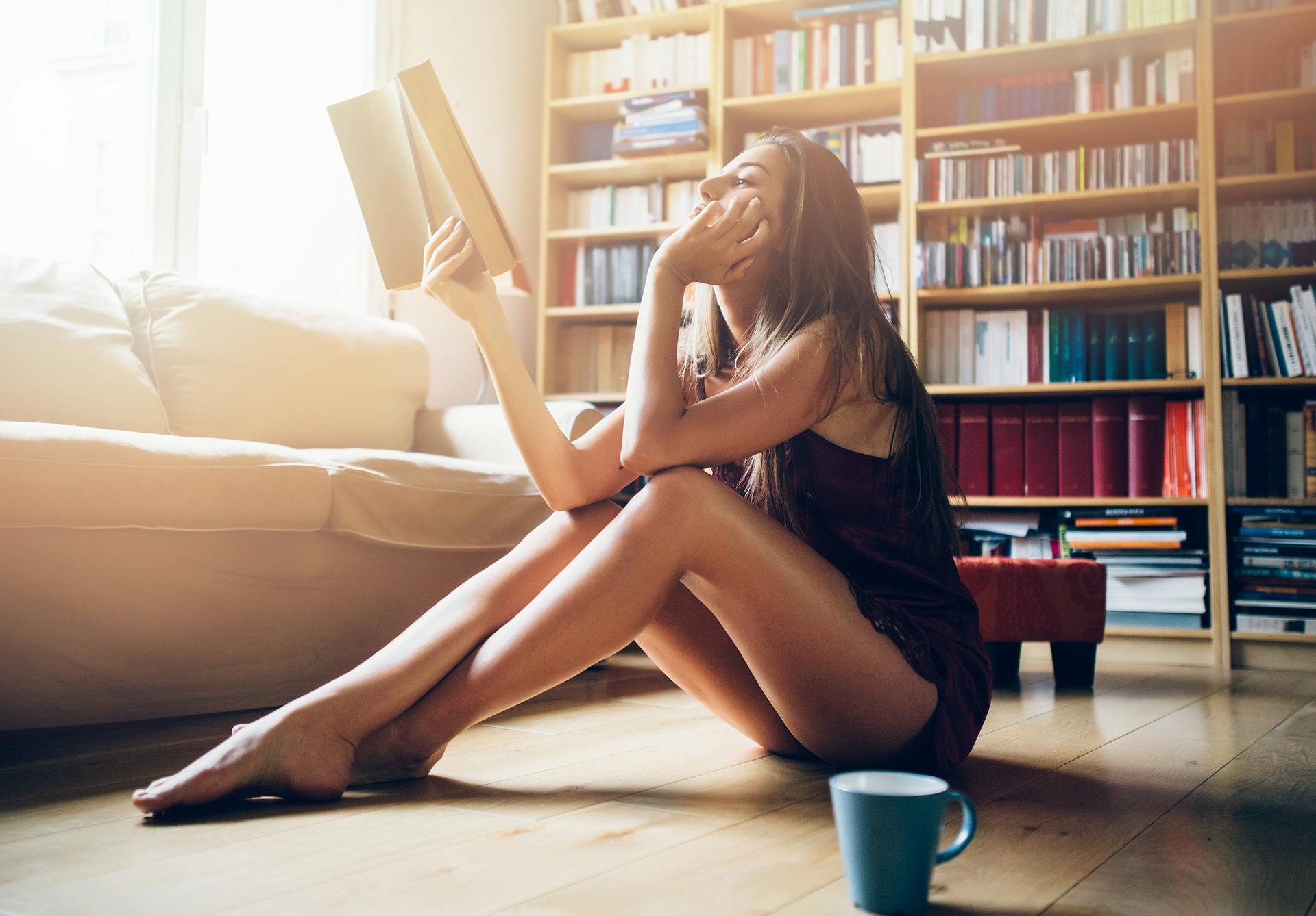 Woman sitting on the floor reading a book wearing short shorts